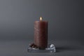 Burning candle with coffee beans on grey background Royalty Free Stock Photo