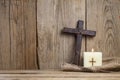 Burning candle and cross on wooden background