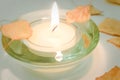 Burning candle and dry autumn leaves on a white table Royalty Free Stock Photo