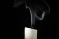 Burning candle with fading flame and smoke on a black background