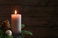 Burning candle on fir branches with Christmas ball and decoration against a rustic wooden wall, advent light in the dark season, Royalty Free Stock Photo