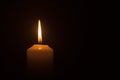 A burning candle flame isolated on black or dark background on table in church for Christmas, funeral and memorial service Royalty Free Stock Photo