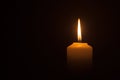 A burning candle flame isolated on black or dark background on table in church for Christmas, funeral and memorial service Royalty Free Stock Photo