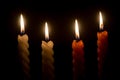 Burning candle flames or lights glowing on three spiral white and orange candles on black or dark background on table in church Royalty Free Stock Photo
