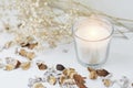 Burning candle with floral decor on a white table. Cozy and hygge background Royalty Free Stock Photo