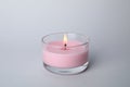 Burning candle in glass holder on light grey background Royalty Free Stock Photo