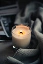 Burning candle in glass with wooden wick, handmade natural wax candle with knitted blanket Royalty Free Stock Photo