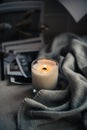 Burning candle in glass with wooden wick, handmade natural wax candle with knitted blanket Royalty Free Stock Photo