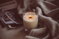 Burning candle in glass with wooden wick, handmade natural wax candle with knitted blanket Royalty Free Stock Photo