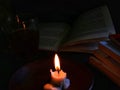 a burning candle illuminates the reading book