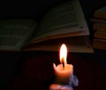 a burning candle illuminates the reading book