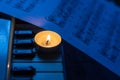 A burning candle on the keys of the synthesizer near the sheets with notes Royalty Free Stock Photo