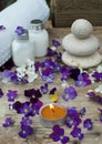 Burning candle in the middle of purple pansy flowers and a spa set with skin lotion Royalty Free Stock Photo