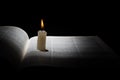 Burning candle on opened book on black background Royalty Free Stock Photo