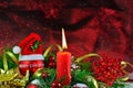 Burning candle with red bauble with Santa hat and Christmas decorations Royalty Free Stock Photo