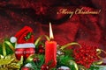 Burning candle with red bauble with Santa hat and Christmas decorations Royalty Free Stock Photo