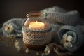 Burning candle in small amber glass jar, flowers of gypsophila and stack knitted seasin sweaters Cozy lifestyle, hygge concept.