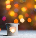 Burning candle, in snow, with defocussed fairy lights, boke in the background, Festive Christmas background Royalty Free Stock Photo