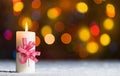 Burning candle, in snow, with defocussed fairy lights, bokeh in the background, Festive Christmas background Royalty Free Stock Photo