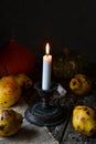 burning candle surrounded by ripe pears on a wooden table
