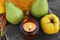 Burning candle, tasty fruits and beautiful dry leaves on wooden surface, above view. Autumn atmosphere