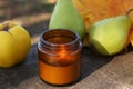 Burning candle, tasty fruits and beautiful dry leaves on wooden surface outdoors, closeup. Autumn atmosphere