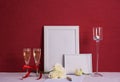 Burning candle, two glasses with champagne, writing materials, white roses, white photo frames on a red background Royalty Free Stock Photo