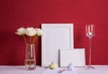 Burning candle, writing materials, white roses in a glass vase, white photo frames on a red background Royalty Free Stock Photo