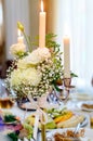 Burning candles in a candlestick, decorated with flowers stand on a table in the restaurant Royalty Free Stock Photo