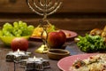 Burning candles in candlesticks Star of David on Shabbat Traditional Jewish food on the laid table, fruits, menorah.
