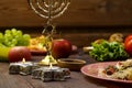 Burning candles in candlesticks Star of David on Shabbat Traditional Jewish food on the laid table, fruits, menorah.