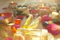 Burning candles with essential spa oil, rose flower petals and colorful gems on wooden background Royalty Free Stock Photo