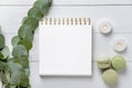 Burning candles with eucalyptus branches, notebook and macaroons on white wooden background Royalty Free Stock Photo