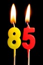 Burning candles in the form of 85 eighty five figures numbers, dates for cake isolated on black background. The concept of cel