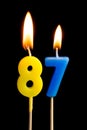 Burning candles in the form of 87 eighty seven numbers, dates for cake isolated on black background. The concept of celebrating