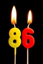 Burning candles in the form of 86 eighty six numbers, dates for cake isolated on black background. The concept of celebrating a