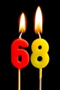 Burning candles in the form of 68 sixty eight numbers, dates for cake isolated on black background. The concept of celebrating a