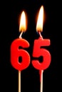 Burning candles in the form of 65 sixty ive figures numbers, dates for cake isolated on black background. The concept of celebra Royalty Free Stock Photo