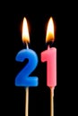 Burning candles in the form of 21 twenty one numbers, dates for cake isolated on black background. The concept of celebrating a