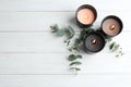 Burning candles and green branches on white wooden table, flat lay. Royalty Free Stock Photo