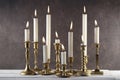 Burning candles in vintage metal candlesticks on white wooden table against dark stone background. Royalty Free Stock Photo