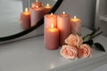 Burning candles and roses on white console table near mirror, space for text Royalty Free Stock Photo