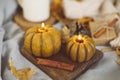 Burning candles shape of pumpkin and autumn decor on bed in bedroom.