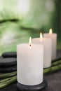 Burning candles, spa stones and bamboo sprouts on grey table against green background Royalty Free Stock Photo