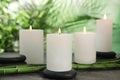 Burning candles, spa stones and bamboo sprouts on grey table against green background Royalty Free Stock Photo