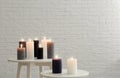 Burning candles on tables against brick wall with space Royalty Free Stock Photo