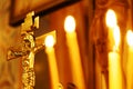 Burning candles in the temple on the background of a golden cross. Symbol of the crucified Jesus Christ Royalty Free Stock Photo