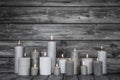 Burning candles in white and grey on wooden shabby chic background.