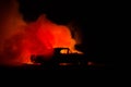 Burning car on a dark background. Car catching fire, after act of vandalism or road indicent