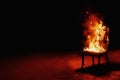 Burning chair on a black background. Conceptual photo burnout at work. Place for an inscription
